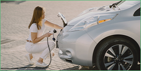 Is the electric vehicle metals boom sustainable? The photo shows a woman connecting an electric car to an energy source.