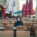 Focus Coface sur l'Allemagne : De nouvelles défaillances en vue. La photo montre une femme portant un masque, assise seule à la terrasse d'un café à Cologne, en Allemagne.